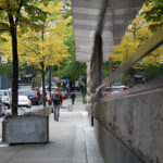 西南主街（SW Main Street）：建筑墙面映出金黄的秋叶和红色的尾灯灯光，左侧路中是标志性的驯鹿雕塑。
